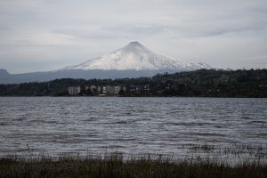 Imagen: territorio del Mallolafken (lago Villarrica), donde se realiza la muestra central de TUWUN. Al fondo el Rukapillan (volcán Villarrica), Wallmapu, territorio Mapuche.